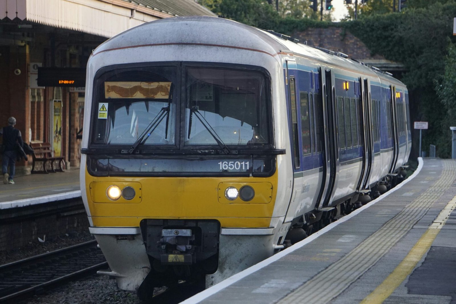 a yellow and white train pulling into a train station