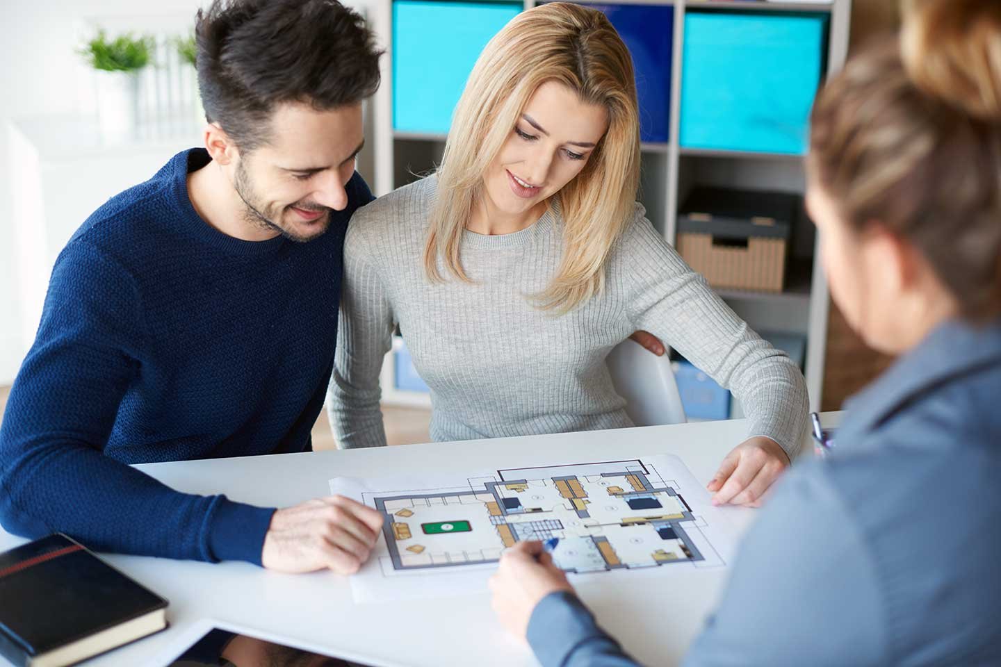 Young couple reviewing house plans with a real estate agent.