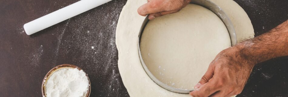 person cutting dough with round cutter